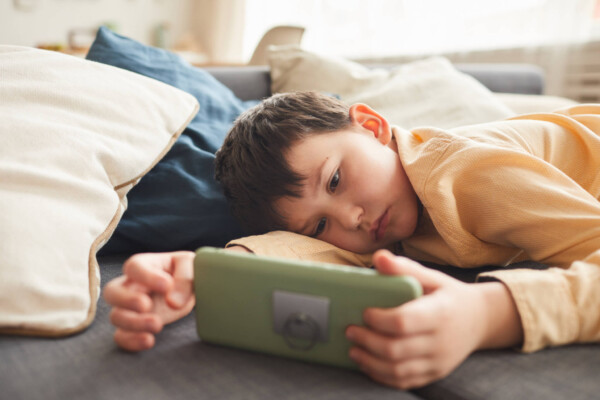 Lazy boy lying on bed watching smartphone