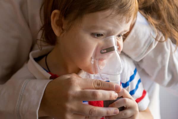 Mother giving her child a nebulizer breathing treatment for respiratory ailment