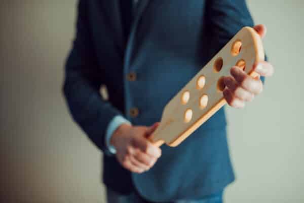 Adult holds a wooden paddle for spanking or corporal punishment