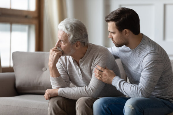 young man embraces upset elderly dad