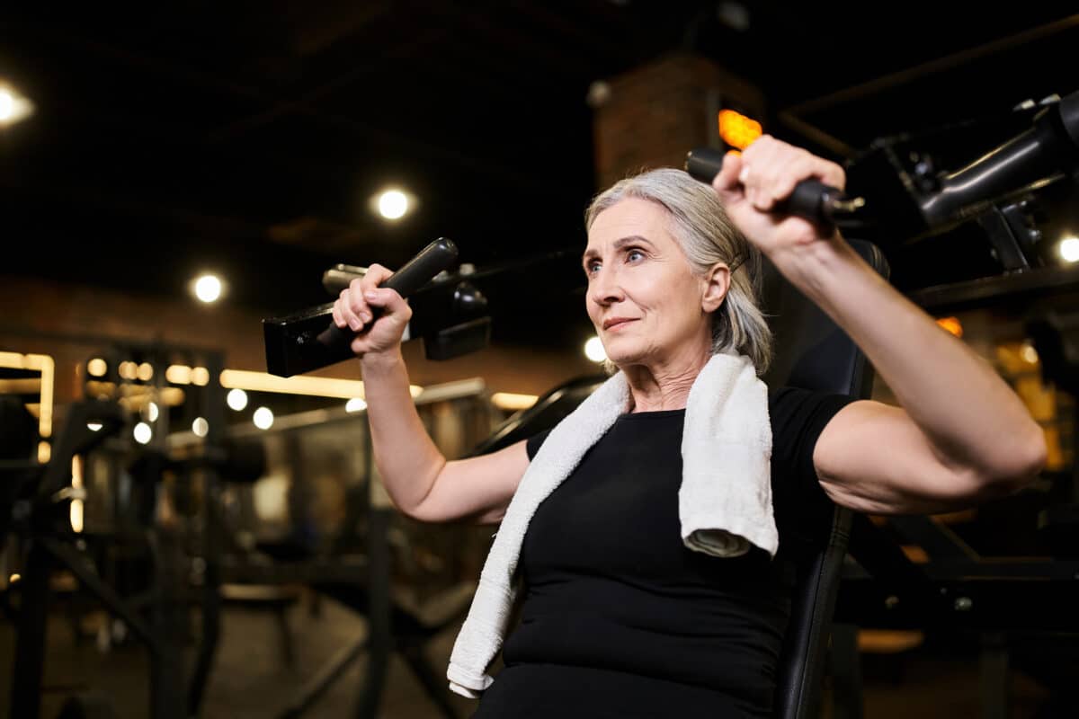 Older woman doing shoulder press at gym