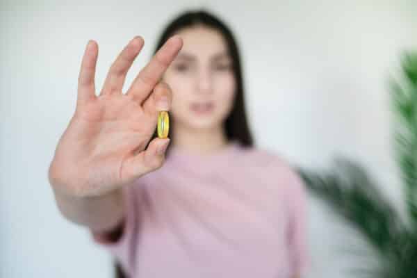 Woman holding an omega-3 fatty acid fish oil supplement