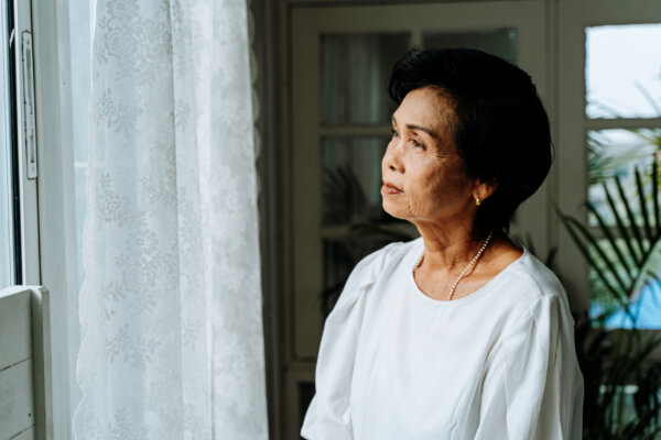 Sad, lonely senior woman looking out the window